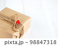 Gift box of craft paper with hearts on the white wooden background. Valentine's Day. 98847318