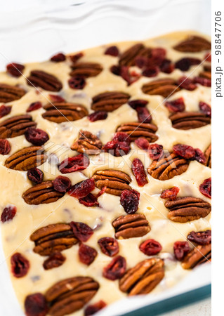 Pouring fudge mixture into the baking pan lined with parchment paper to prepare white chocolate cranberry pecan fudge. 98847706
