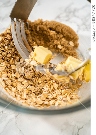 Mixing ingredients in a large glass mixing bowl to bake banana oatmeal muffins. Mixing ingredients in a large glass mixing bowl to bake banana oatmeal muffins. 98847720