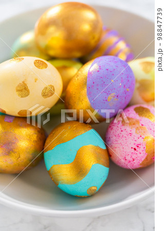 Colored and painted with gold hard-boiled eggs on a marble background. Colored and painted with gold hard-boiled eggs on a marble background. 98847739
