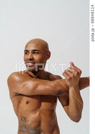 Sportsman with naked torso is warming up on white studio background and looking at side 98848114