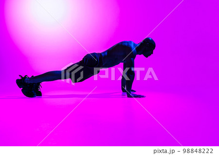 Athlete in plank position does push-ups and arm exercises on studio background Athlete in plank position does push-ups and arm exercises on studio background 98848222