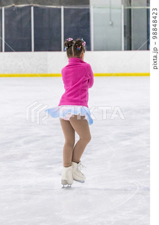 Little girl practicing figure skating on an indoor ice rink. Little girl practicing figure skating on an indoor ice rink. 98848423