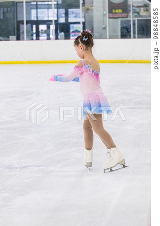 Little girl practicing figure skating on an indoor ice rink. Little girl practicing figure skating on an indoor ice rink. 98848585