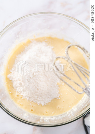 Mixing ingredients in a large glass mixing bowl to bake apple bundt cake with caramel glaze. Mixing ingredients in a large glass mixing bowl to bake apple bundt cake with caramel glaze. 98848620