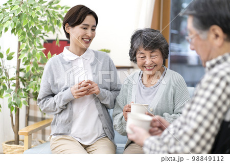 お茶を飲みながら話をする介護士とシニア 98849112