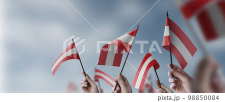 A group of people holding small flags of the Austria in their hands A group of people holding small flags of the Austria in their hands 98850084