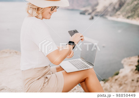 Digital nomad, Business woman working on laptop by the sea. Pretty lady typing on computer by the sea at sunset, makes a business transaction online from a distance. Freelance, remote work on vacation Digital nomad, Business woman working on laptop by the sea. Pretty lady typing on computer by the sea at sunset, makes a business transaction online from a distance. Freelance, remote work on vacation 98850449
