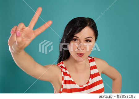 Close-up shot of a beautiful girl posing against a blue background. Close-up shot of a beautiful girl posing against a blue background. 98853195