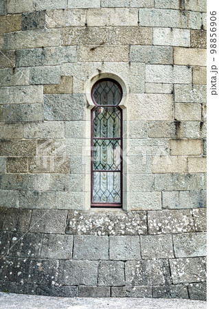 Old medieval window surrounded by stone wall in castle attracts tourists attention. Historical exterior illuminated by bright sunlight Old medieval window surrounded by stone wall in castle attracts tourists attention. Historical exterior illuminated by bright sunlight 98856906