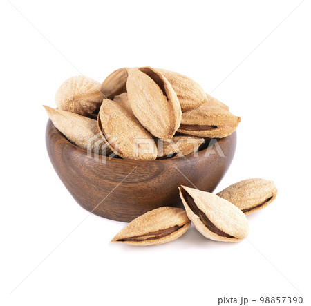 Mountain almonds in wooden bowl, isolated on white background. Uzbek wild almonds. 98857390