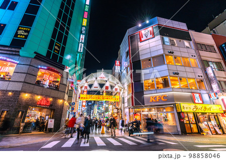 日本の東京都市景観　池袋駅西口・西一番街。スマホゲームに興じる高齢者（左手連打）やウーバーバイク配達 98858046