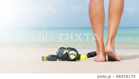 Snorkeling mask on sand beach and woman legs 98858170