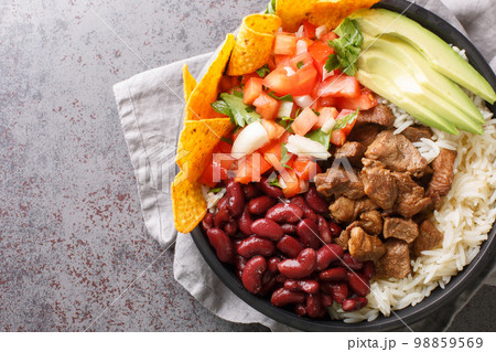 Chifrijo is a delicious traditional Costa Rican dish made with red beans and pork, accompanied by pico de gallo and rice closeup on the plate. Horizontal top view 98859569