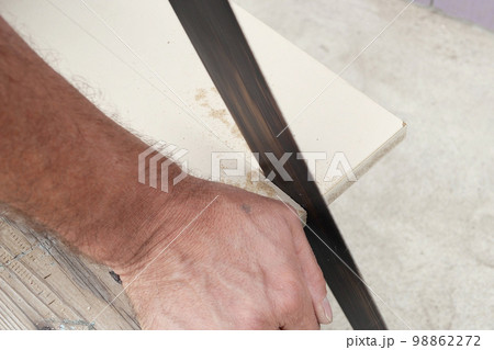 Man cutting through wooden board with hand saw in garden Man cutting through wooden board with hand saw in garden 98862272