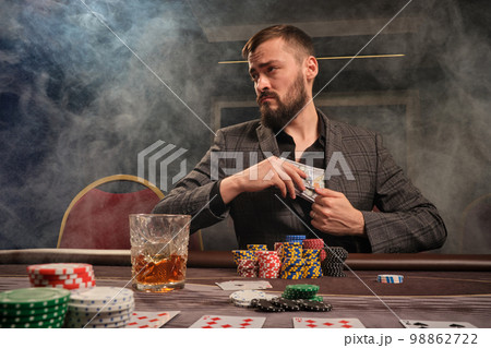 Handsome bearded man is playing poker sitting at the table in casino. Handsome bearded man is playing poker sitting at the table in casino. 98862722
