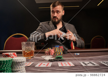 Handsome bearded man is playing poker sitting at the table in casino. Handsome bearded man is playing poker sitting at the table in casino. 98862724