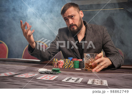 Handsome bearded man is playing poker sitting at the table in casino. Handsome bearded man is playing poker sitting at the table in casino. 98862749