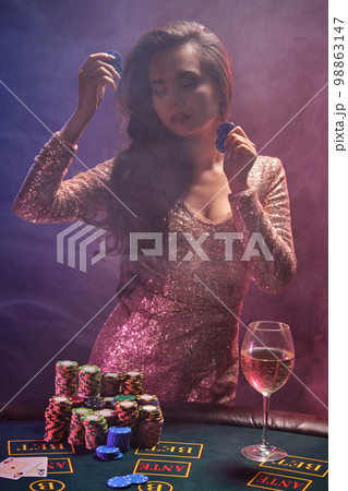 Brunette girl with a perfect hairstyle and bright make-up is posing with gambling chips in her hands. Casino, poker. Brunette girl with a perfect hairstyle and bright make-up is posing with gambling chips in her hands. Casino, poker. 98863147