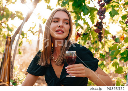 Young blonde woman sitting on a picnic in a vineyard 98863522