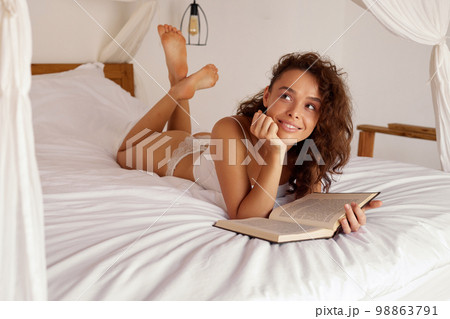 Morning Woman Reading Book. Smiling Girl Read Book While Laying on Bed Morning Woman Reading Book. Smiling Girl Read Book While Laying on Bed 98863791
