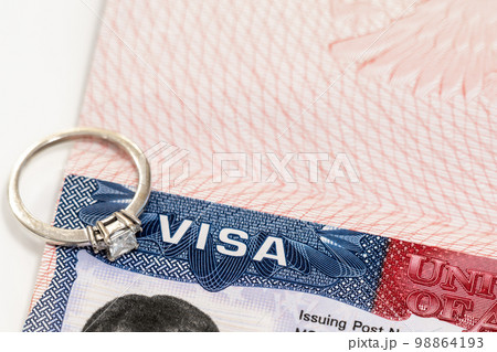 Engagement ring on top of US entry visa sticker in a passport. Conceptual photo for fiance visa and immigration Engagement ring on top of US entry visa sticker in a passport. Conceptual photo for fiance visa and immigration 98864193