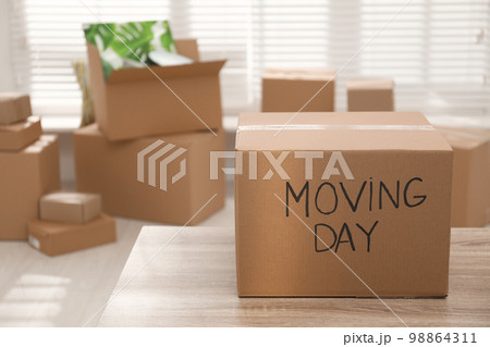 Cardboard box with words MOVING DAY on wooden table Cardboard box with words MOVING DAY on wooden table 98864311