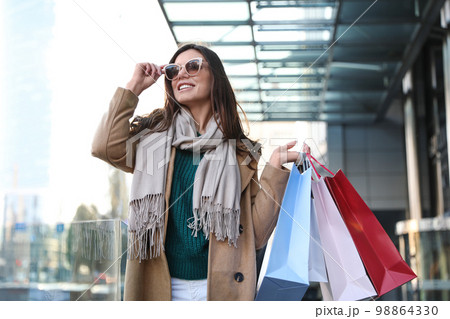 Beautiful young woman with shopping bags on city street Beautiful young woman with shopping bags on city street 98864330