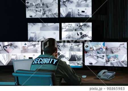 Security guard monitoring modern CCTV cameras in office 98865983