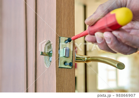 Door latch plate is fastened with fixing screw, locksmith tightens fastener with screwdriver. 98866907