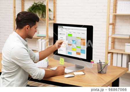Handsome man using calendar app on computer in office 98867066
