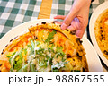 Female hands taking slices of authentic Italian caesar stone oven pizza with arugula, sauce, grilled chicken, herbs and spicy parmesan cheese. 98867565
