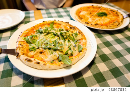 Fresh homemade authentic italian stone oven caesar pizza with arugula, sauce, grilled chicken, herbs and spicy parmesan cheese and margherita. 98867852
