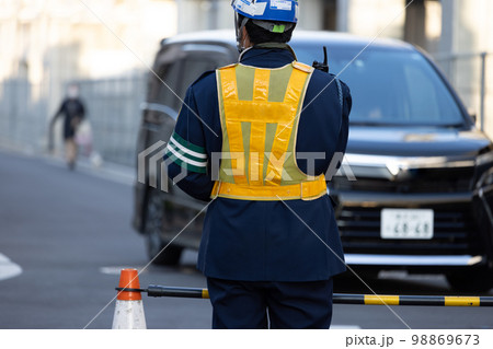 工事現場の交通を誘導する黄色い反射ベストを着た交通誘導員 工事現場の交通を誘導する黄色い反射ベストを着た交通誘導員 98869673