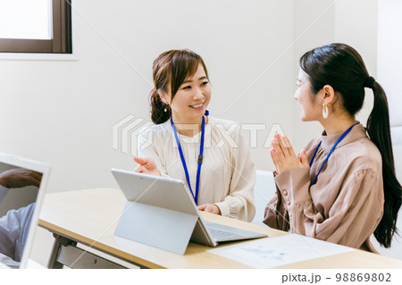 会社のオフィス・会議室で若いスタッフに教えるビジネスウーマン（教育・研修・アジア人・日本人・中国人） 98869802