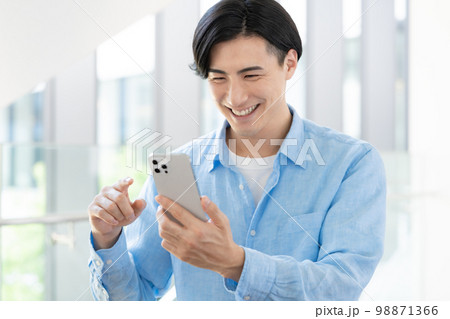 スマホを操作する若いオフィスカジュアルなビジネスマン 撮影協力「LINK FOREST] 98871366