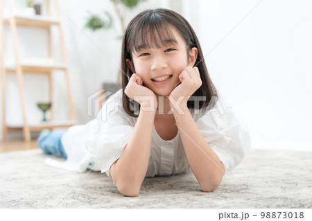 頬杖をついて寝転ぶ女の子 98873018
