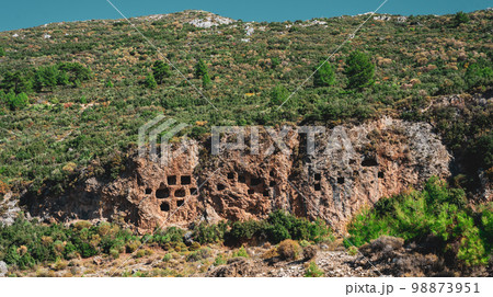 Ruins of the rock tombs of the ancient city, in the mountains of Turkey, Antalya Ruins of the rock tombs of the ancient city, in the mountains of Turkey, Antalya 98873951