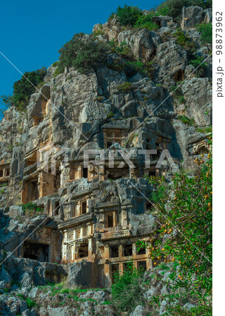 Ruins of Rock-cut tombs in ancient Lycian city of Myra. Lycian way, Demre, Antalya province, Turkey. Ruins of Rock-cut tombs in ancient Lycian city of Myra. Lycian way, Demre, Antalya province, Turkey. 98873962