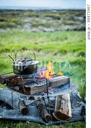 キャンプギア ランプ 焚き火 焚き火台 炎 ランタン オイルランタン ケトル 自然 芝生 98873967