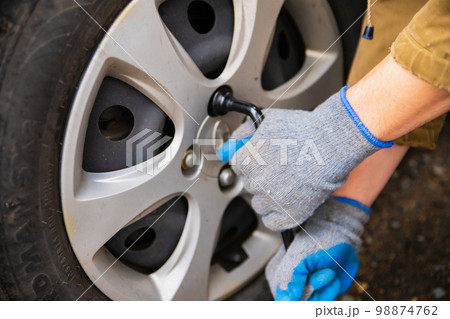 Hyundai wheel change, car is jacked up. Male hands unscrews wheel washers by ball wrench. Astana, Kazakhstan - 10.24.2022 Hyundai wheel change, car is jacked up. Male hands unscrews wheel washers by ball wrench. Astana, Kazakhstan - 10.24.2022 98874762