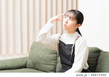 ソファーに座って悩んでいる若い女性 ソファーに座って悩んでいる若い女性 98875400