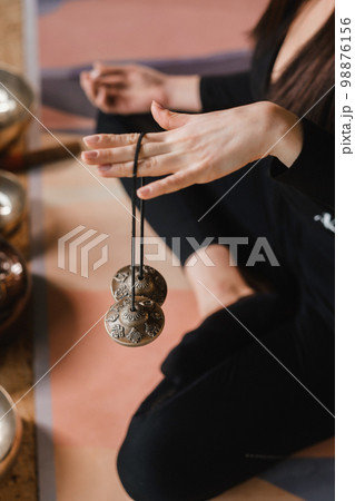 Close-up of a woman's hand holding Tibetan bells for sound therapy. Tibetan cymbals 98876156