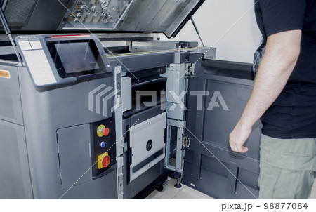 A man worker and a large industrial powder 3d printer in a laboratory in a factory. Multi Jet Fusion. Industrial equipment. New modern 3D printing , additive progressive technology. MJF 98877084