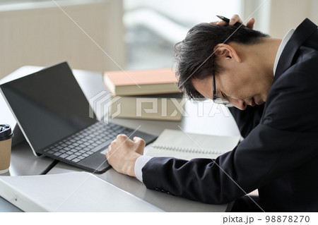 頭を抱えて悩むアジア人ビジネスマン 98878270