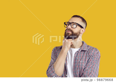 Man in glasses thinking about something and looking away at yellow copy space background Man in glasses thinking about something and looking away at yellow copy space background 98879668