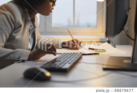 Woman auditor checking financial documents over office desk with magnifying glass 98879677