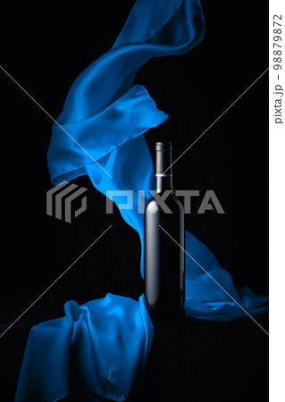 Bottle of red wine and flutters of blue cloth. Bottle of red wine and flutters of blue cloth. 98879872