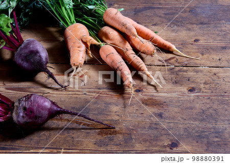 Fresh root crops dug up in vegetable growers garden, carrots and beets with tops lie on table boards. Fresh root crops dug up in vegetable growers garden, carrots and beets with tops lie on table boards. 98880391