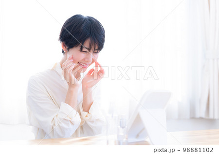 スキンケアで鏡をのぞき込む女性 スキンケアで鏡をのぞき込む女性 98881102